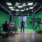 A stylized virtual production workspace with motion capture equipment, green screens, and LED lighting used for modern acting and filmmaking.